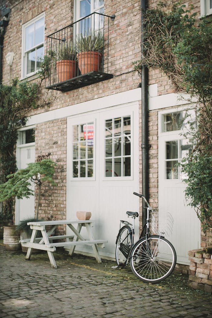 Quaint brick building exterior in London with bicycle and potted plants.
